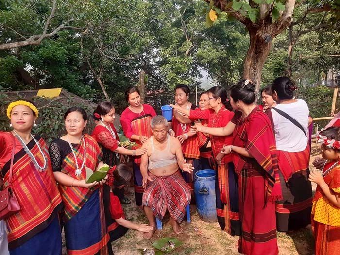 ফুল ভাসানোর পর বাড়িতে গিয়ে বয়োজ্যেষ্ঠদের স্নান করান তরুণ-তরুণীরা।