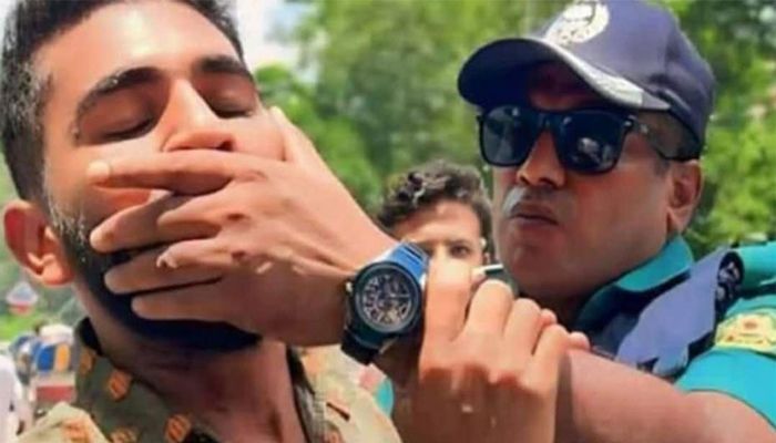 শিক্ষার্থীর মুখ চেপে ধরে রেখেছে পুলিশ সদস্য। ফাইল ছবি 
