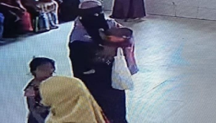 বোরকা পরা সেই নারী, যিনি শিশুটিকে নিয়ে পালাচ্ছেন। ছবি: নোয়াখালী প্রতিনিধি